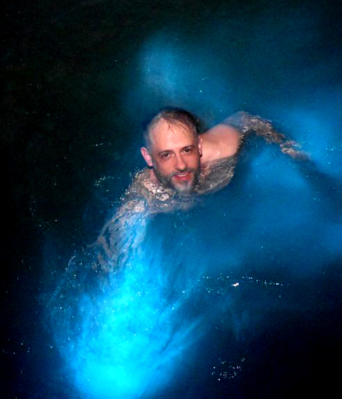 guy swimming in lagoon surrounded by blow glowing water